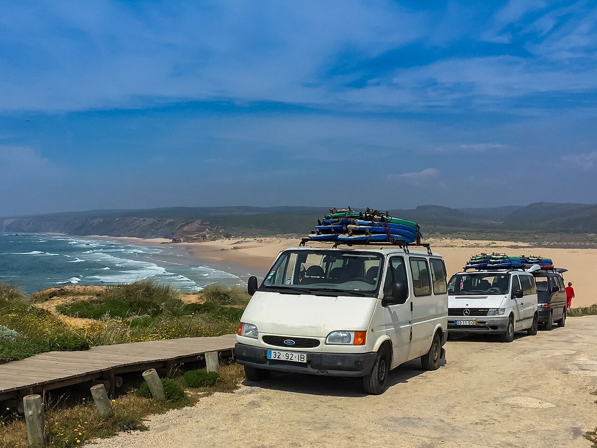 Furgonetas de una escuela de surf con las tablas en la baca, en el Algarve (Portugal).